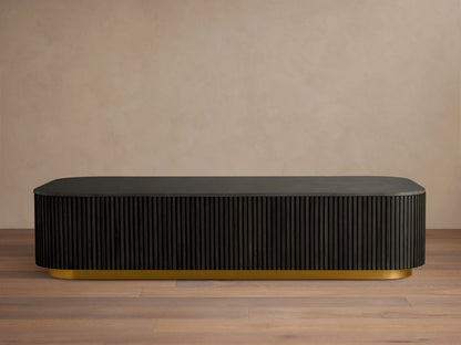 Finnley Coffee Table with a rectangular shape, ebony finish, ribbed sides, and a brass-finished base, on a wooden floor.