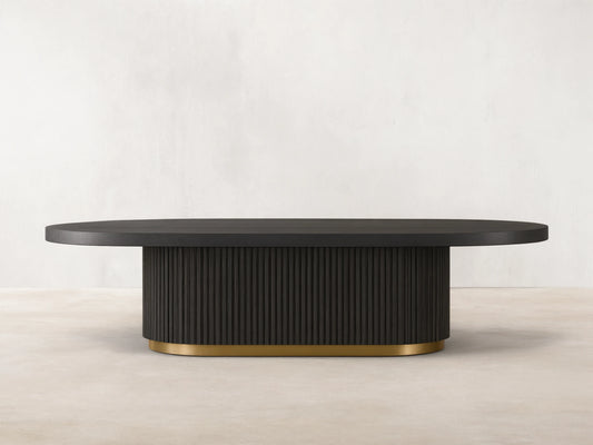 Finnley Coffee Table with a rectangular shape, ebony finish, ribbed sides, and a brass-finished base, on a wooden floor.