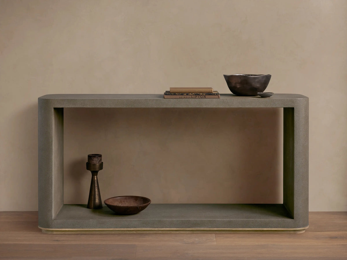 Harrow Console Table with gray faux shagreen texture, rectangular shape, wooden base. Holds books and dark bowls on top, candle and dish below.
