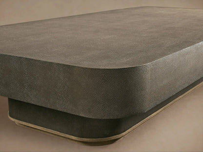 Rectangular Harrow Coffee Table with a faux shagreen surface in muted olive tones, resting on a pedestal base, on hardwood floor.