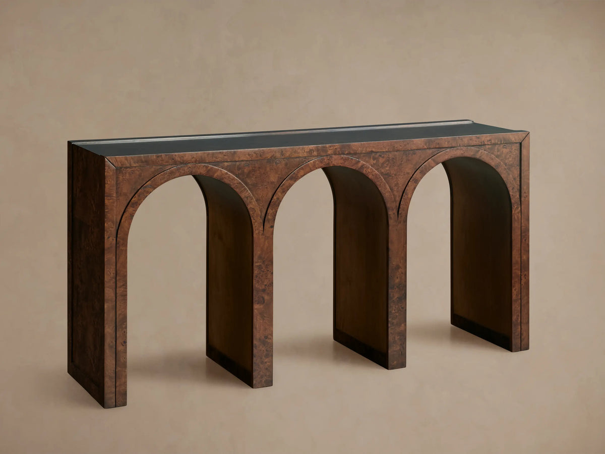 Hattie Burl Console Table: brown burl wood with three arches, dark top, neutral bowl & small decor items on top, against a beige wall.