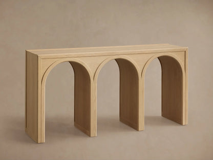 Oak Hattie Console Table with three arch-shaped supports, light wood finish, vase, book, and candle displayed on top.