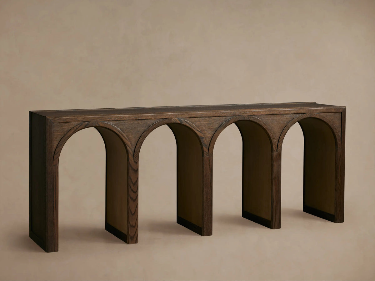 Hattie Console Table in dark oak with arch design, contrasting interior, decorated with books, a vase, and a small object.