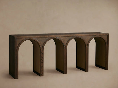 Hattie Console Table in dark oak with arch design, contrasting interior, decorated with books, a vase, and a small object.