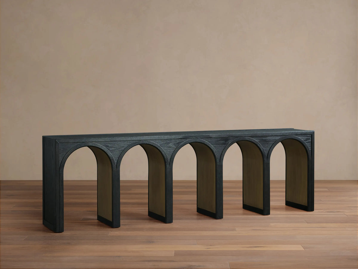 Hattie Console Table with black arches and contrasting interiors, holding a decorative vase and two tall candle holders on top.