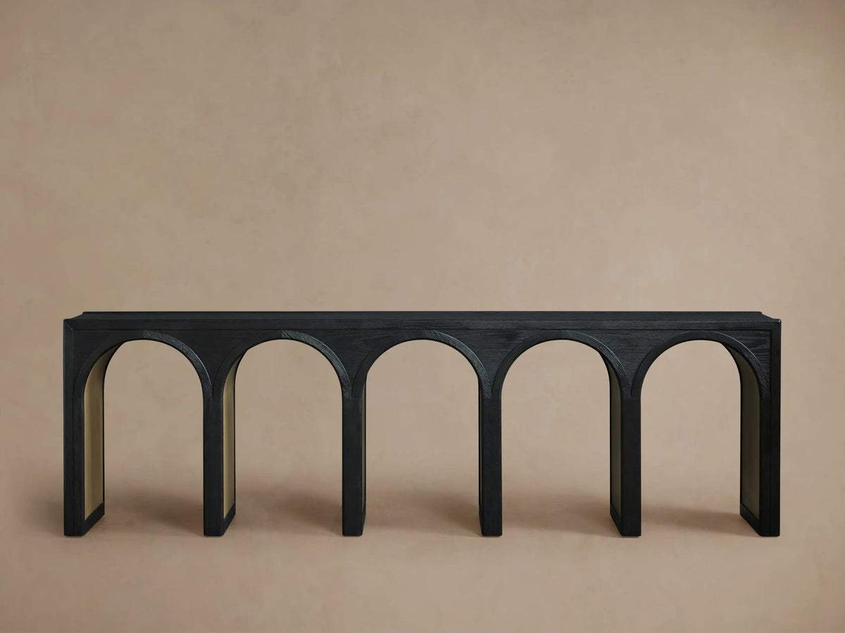 Hattie Console Table with black oak top, arched design, and contrasting interior finish on a beige background.
