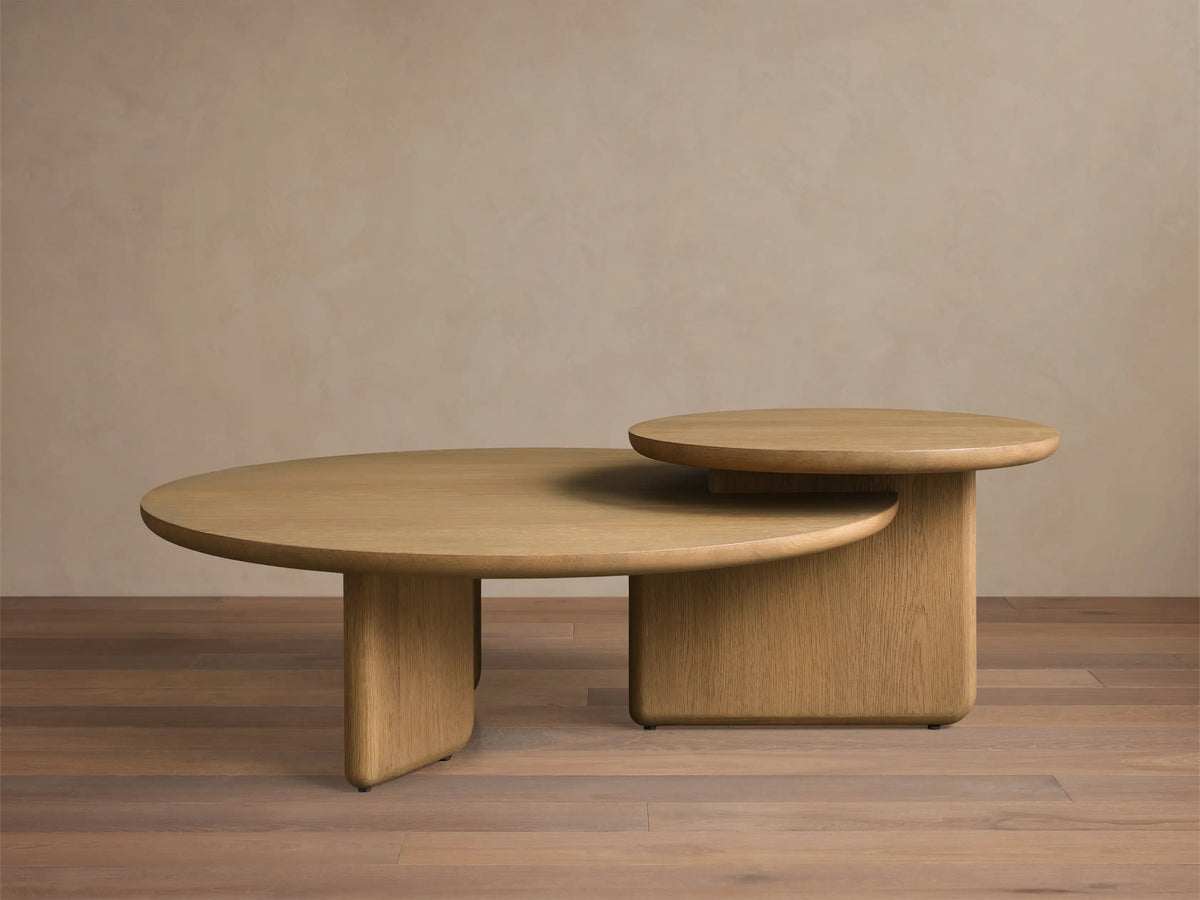 Front view of the light oak Nested Coffee Table Set, showing two round tables with thick bases, one partially tucked under the other.
