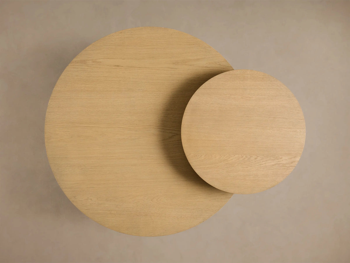 Top-down view of two overlapping light beige circular wooden tables with visible grain, one large and one smaller.
