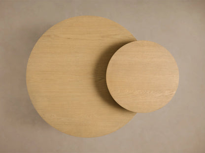 Top-down view of two overlapping light beige circular wooden tables with visible grain, one large and one smaller.