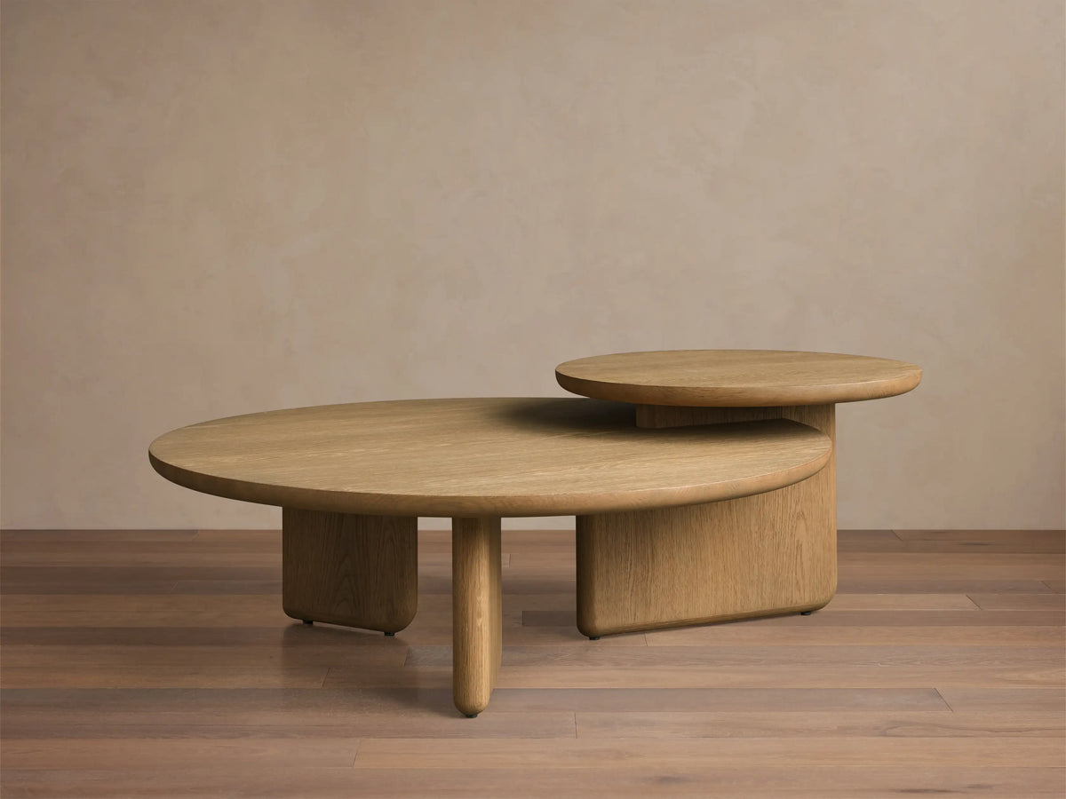 Close-up of two overlapping round light wood coffee tables with visible grain and smooth, rounded edges.