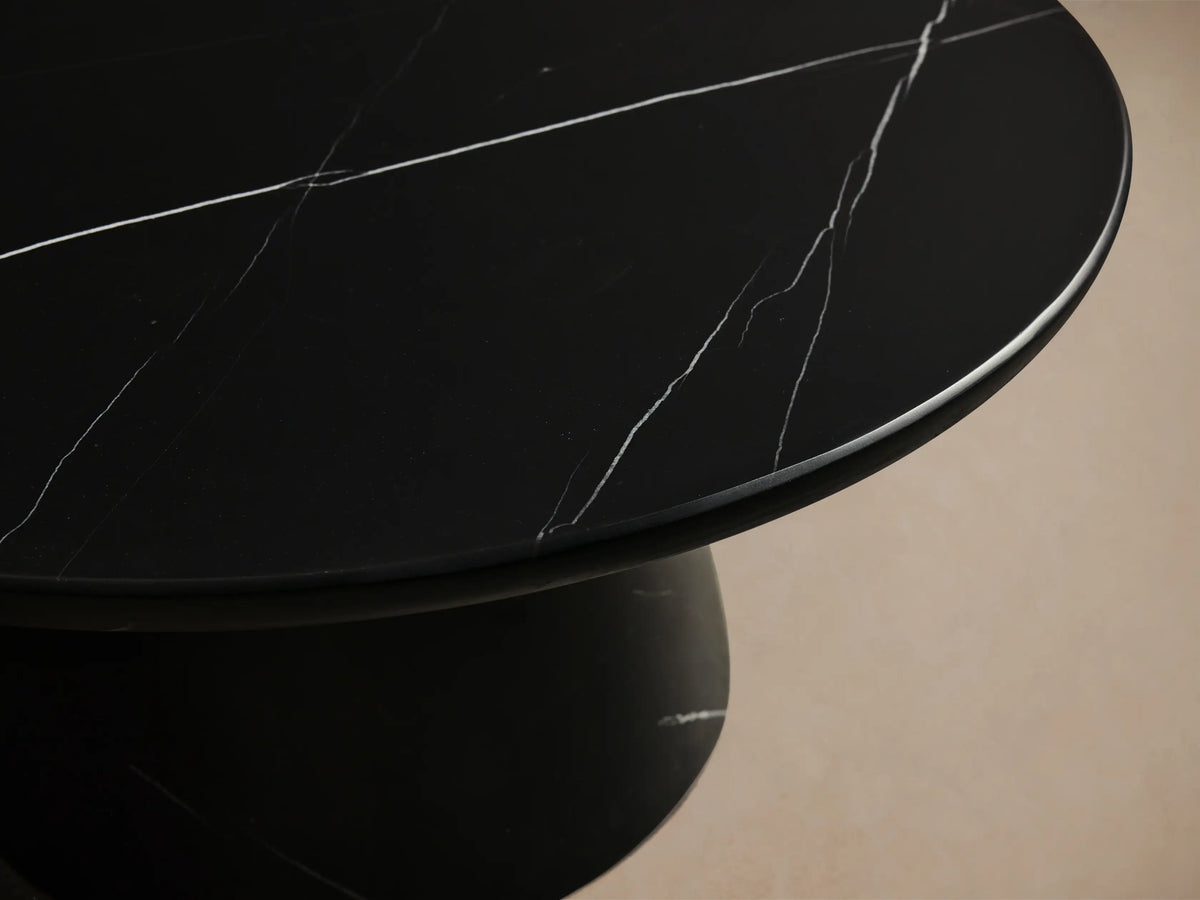 Four Hemmings black marble nesting coffee tables with white veining and round tops, set on a wood floor.