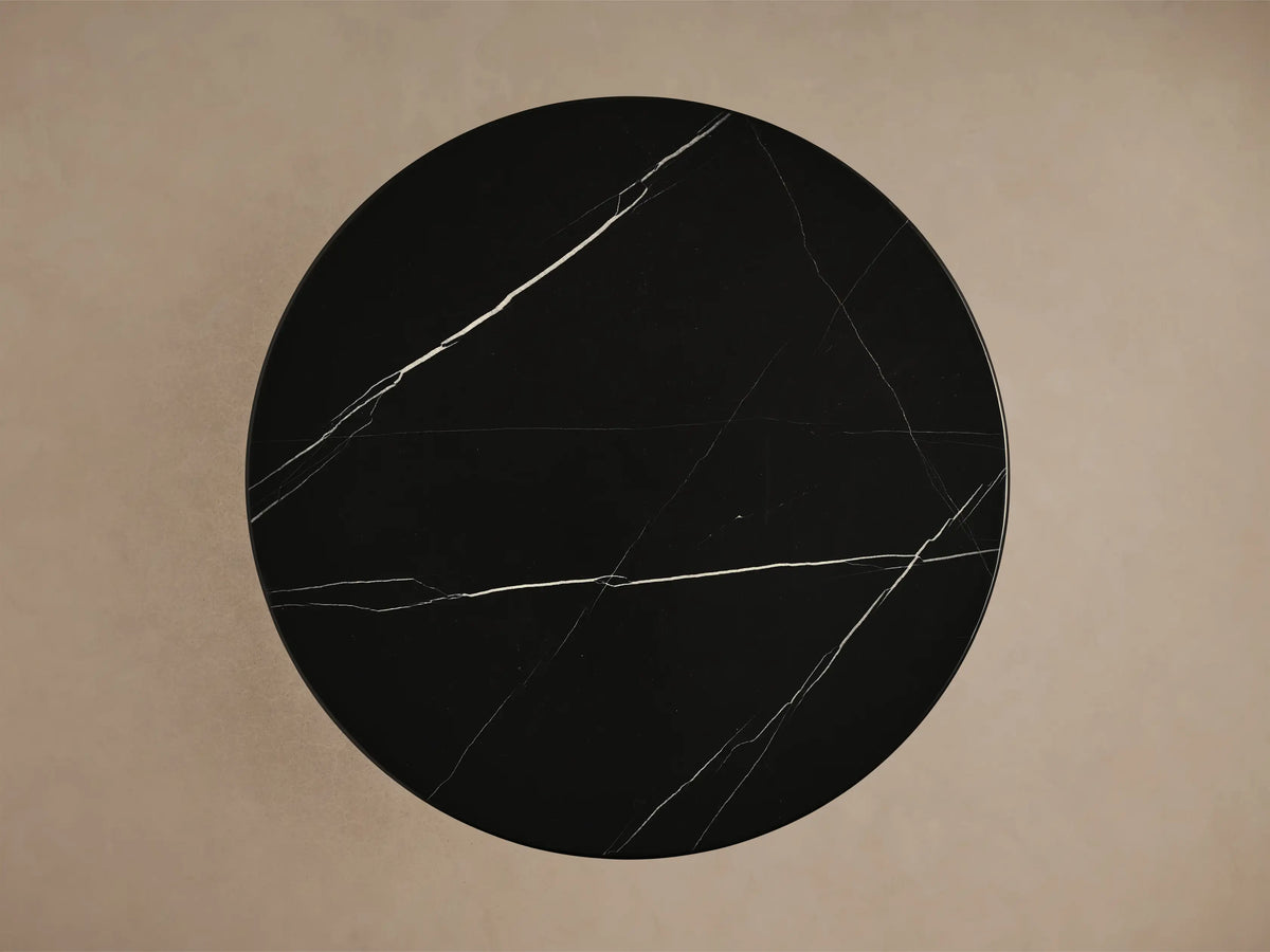 Close-up of Hemmings Stone Nesting Coffee Table's black Marquina marble tabletop with prominent white veining, reflecting on its dark base.