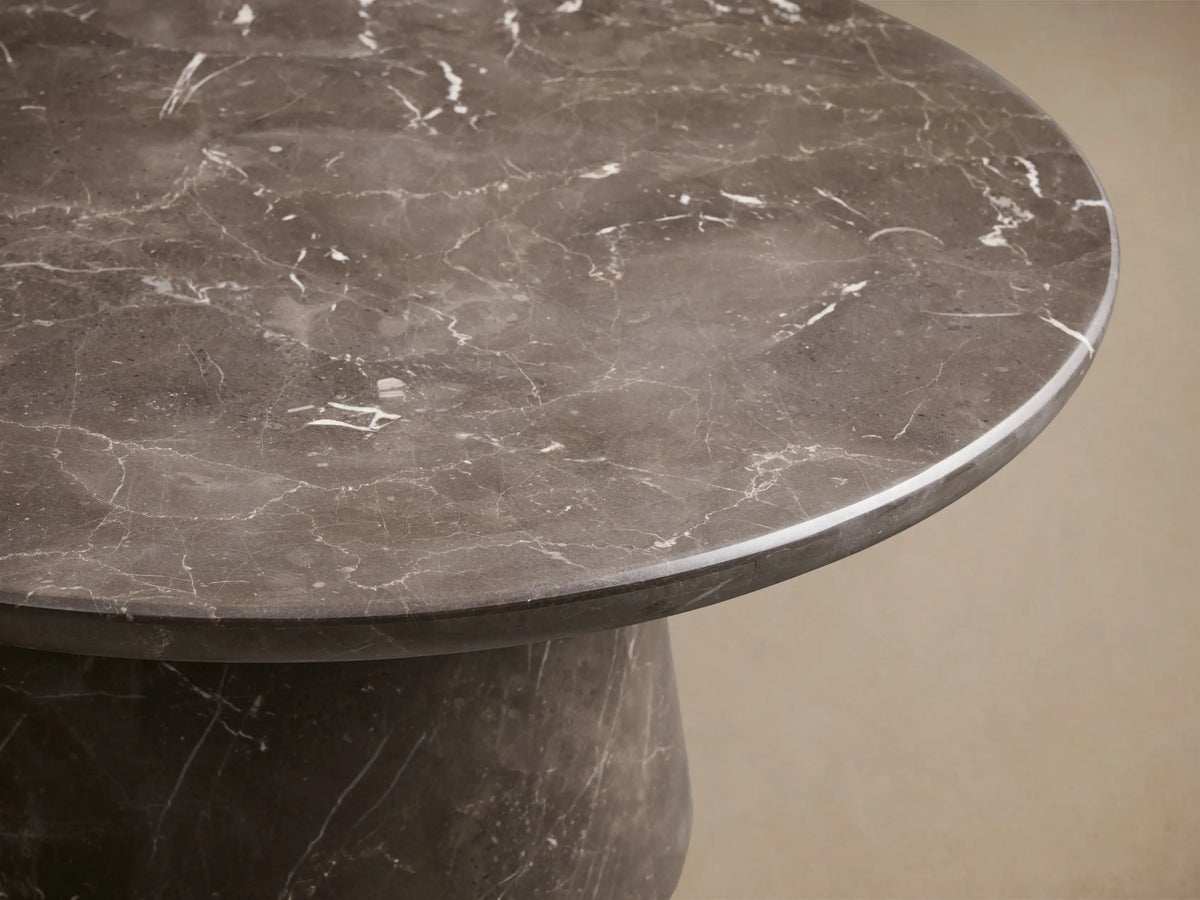 Front view of a dark gray round marble coffee table with prominent white veining, featuring a thick round top and a conical base.