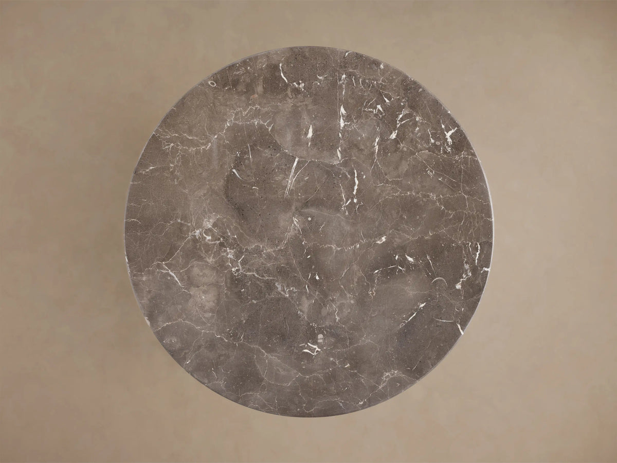Close-up of the round dark grey marble table top with white veining.