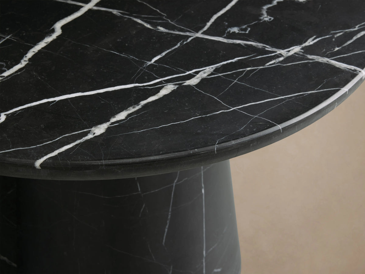 Hemmings Stone Nesting Coffee Table with black marquina marble top, cylindrical base, white veining, on wooden floor.