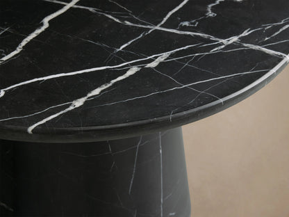 Hemmings Stone Nesting Coffee Table with black marquina marble top, cylindrical base, white veining, on wooden floor.