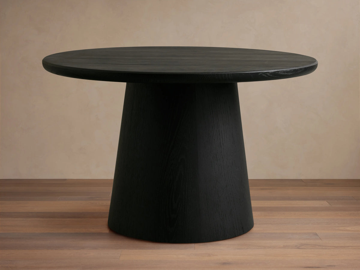 Black round Hemmings Nesting Coffee Table with a smooth dark wood veneer finish. The table has a conical base and rests on a light wood floor.