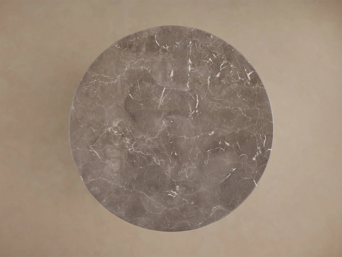 Top-down view of a circular gray marble surface with white veining.