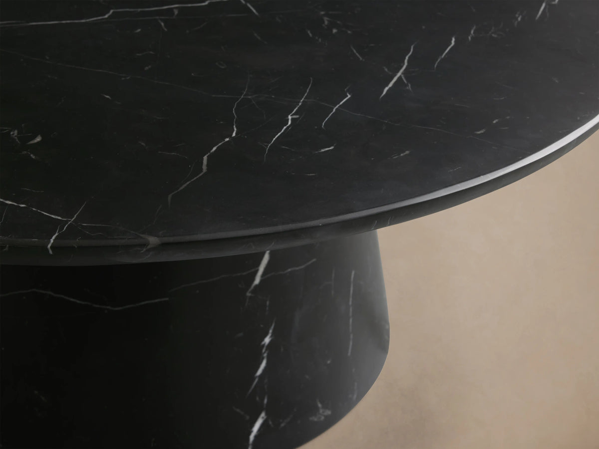 Hemmings Stone Nesting Coffee Table with a round black marble top and cylindrical base, featuring white veining, on a wooden floor.