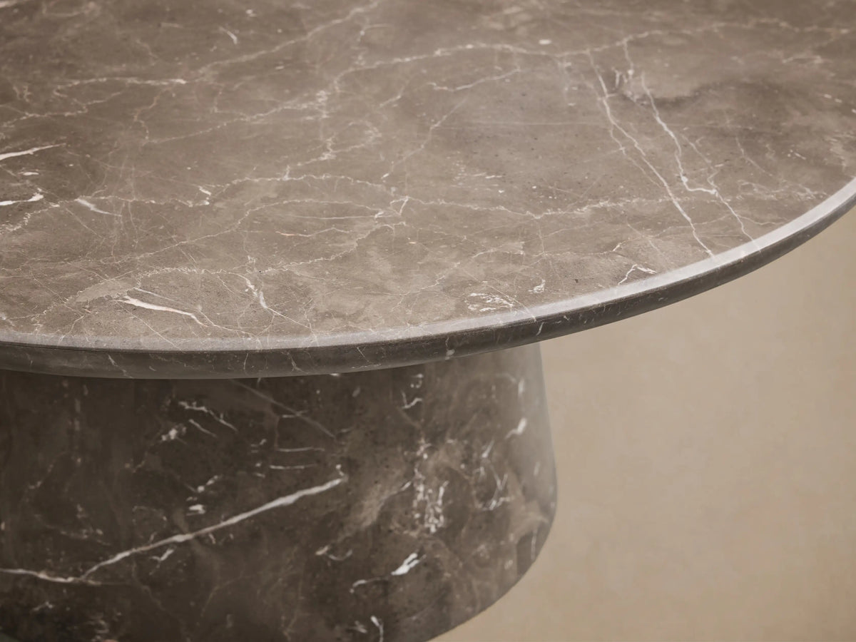 Top-down view of a circular dark gray marble slab, detailed with striking white veining throughout its surface.