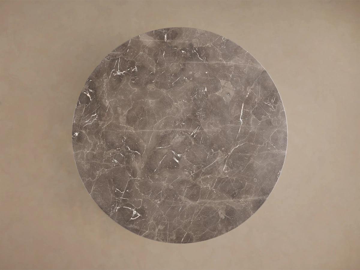 Front view of a round dark gray marble dining table with a thick pedestal base and white veining.