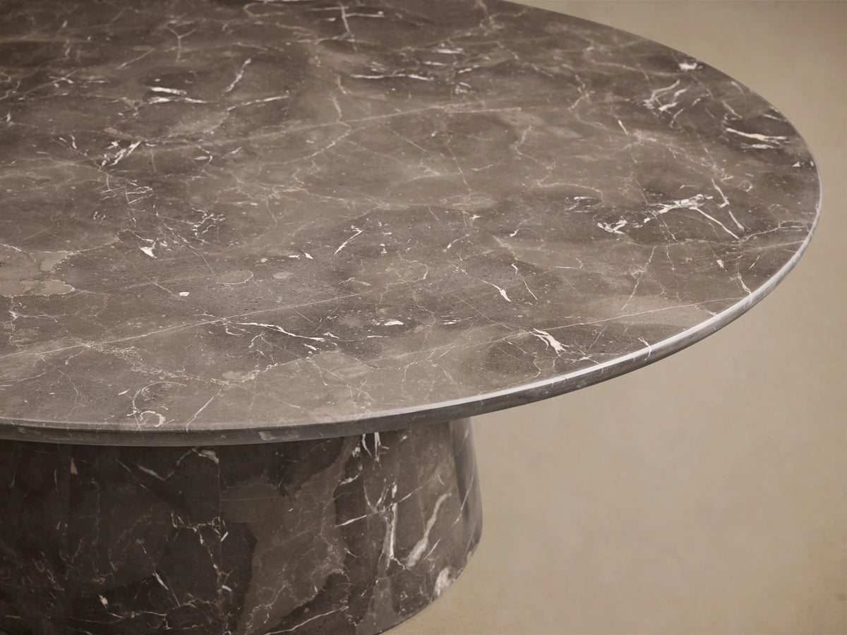 Overhead view of a round dark grey marble tabletop with intricate white veining.
