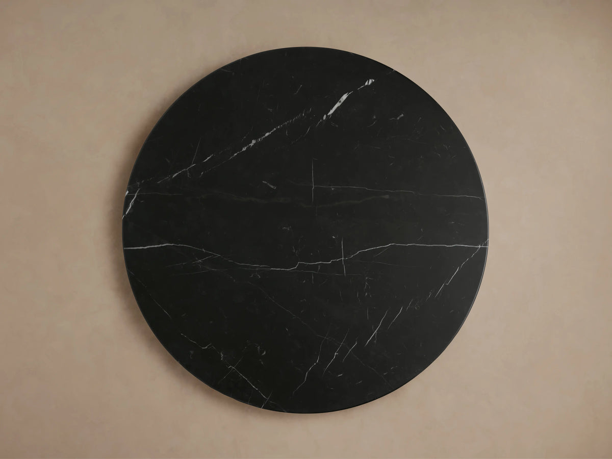 Close-up of Hemmings Stone Nesting Coffee Table. Round black marquina marble top with white veining on a black marble base.