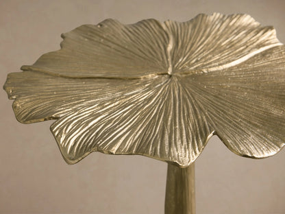 Close-up of a brushed gold metallic leaf sculpture with deep, textured veins and organic edges.