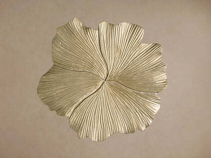 Top view of a gold metallic leaf-shaped decorative object with prominent, intricate radial veins and a textured surface.