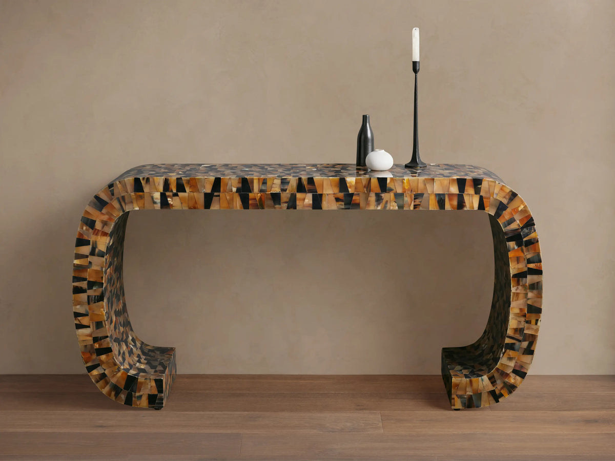 Lindly Console Table with rounded U-shape, intricate mosaic of natural brown, black, amber horn pieces. On a wooden floor.