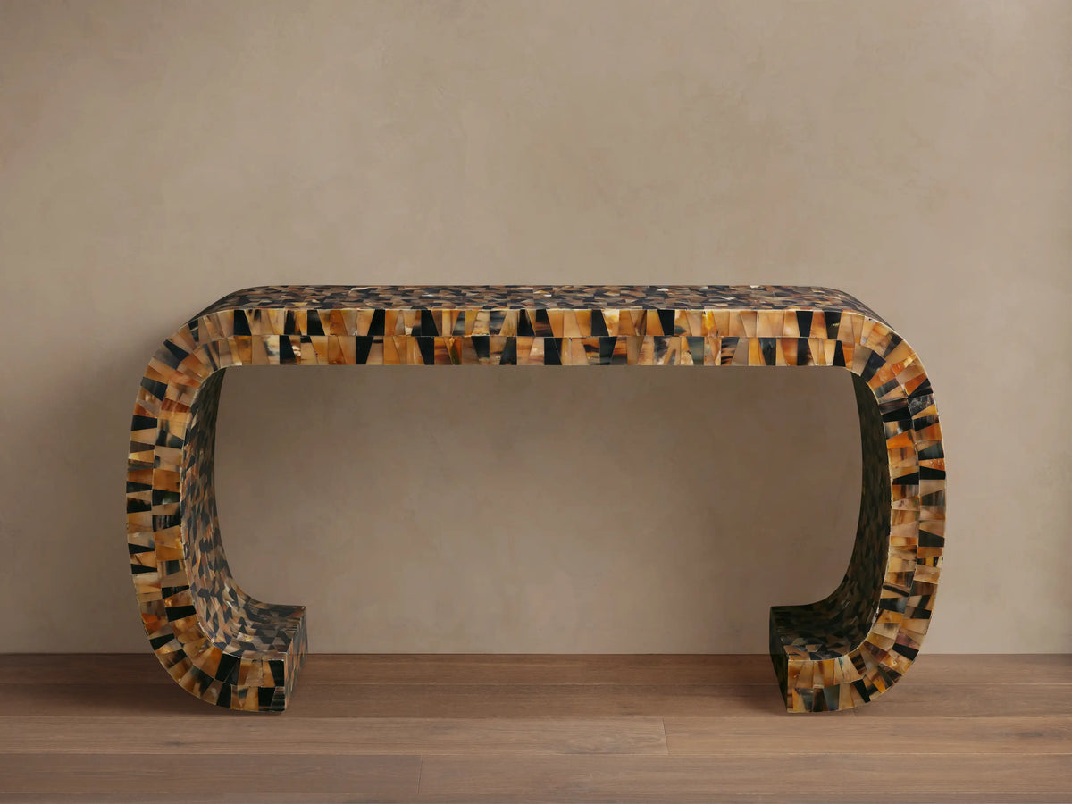 Interior view of Lindly Console Table with a rounded silhouette, detailed with mosaic-like natural buffalo horn in brown and black. Flowers on top.