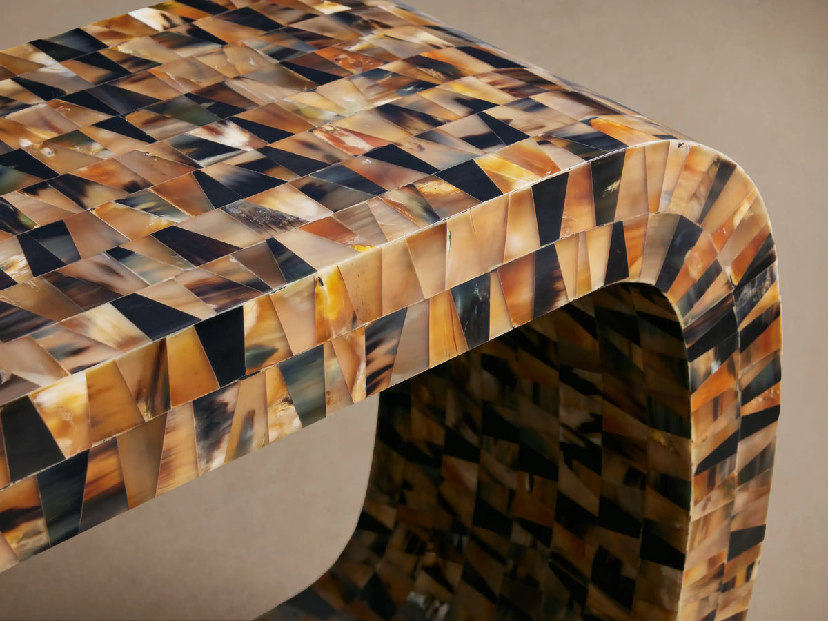 Lindly Console Table, U-shaped, made of mosaic natural buffalo horn pieces in brown, amber, and black, against a plain wall.