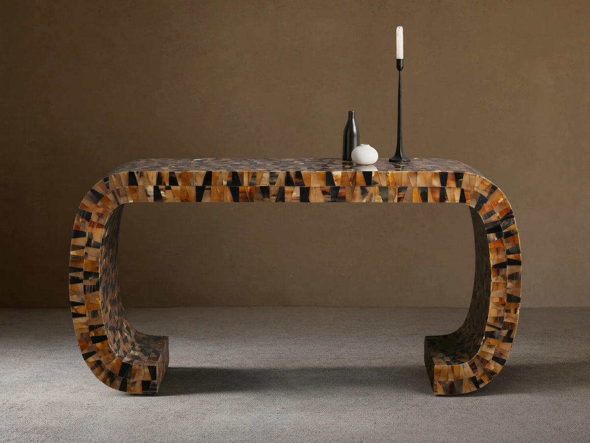 Lindly Console Table with rounded U-shape, intricate mosaic of natural brown, black, amber horn pieces. On a wooden floor.