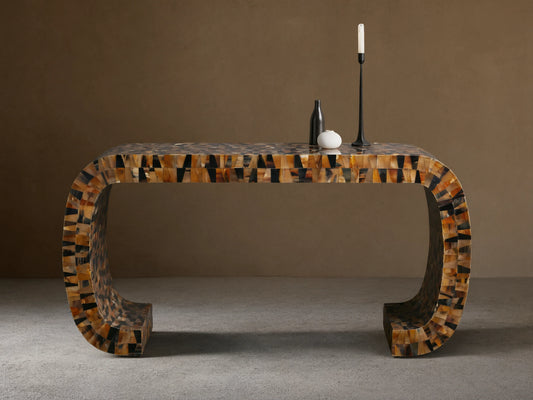 Lindly Console Table with rounded U-shape, intricate mosaic of natural brown, black, amber horn pieces. On a wooden floor.