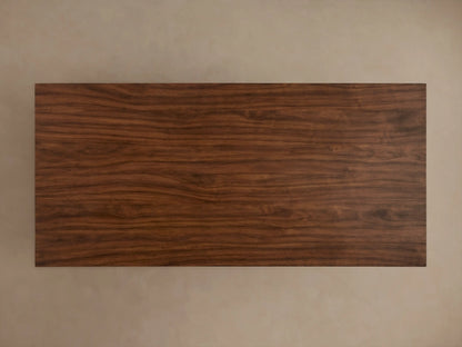 Ilaria Coffee Table with a sleek rectangular wooden top and a wide, trapezoidal base. The rich brown wood grain is prominently visible.