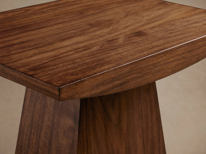 Ilaria End Table made of dark brown wood, showing a trapezoidal top and a tapered base against a neutral background.