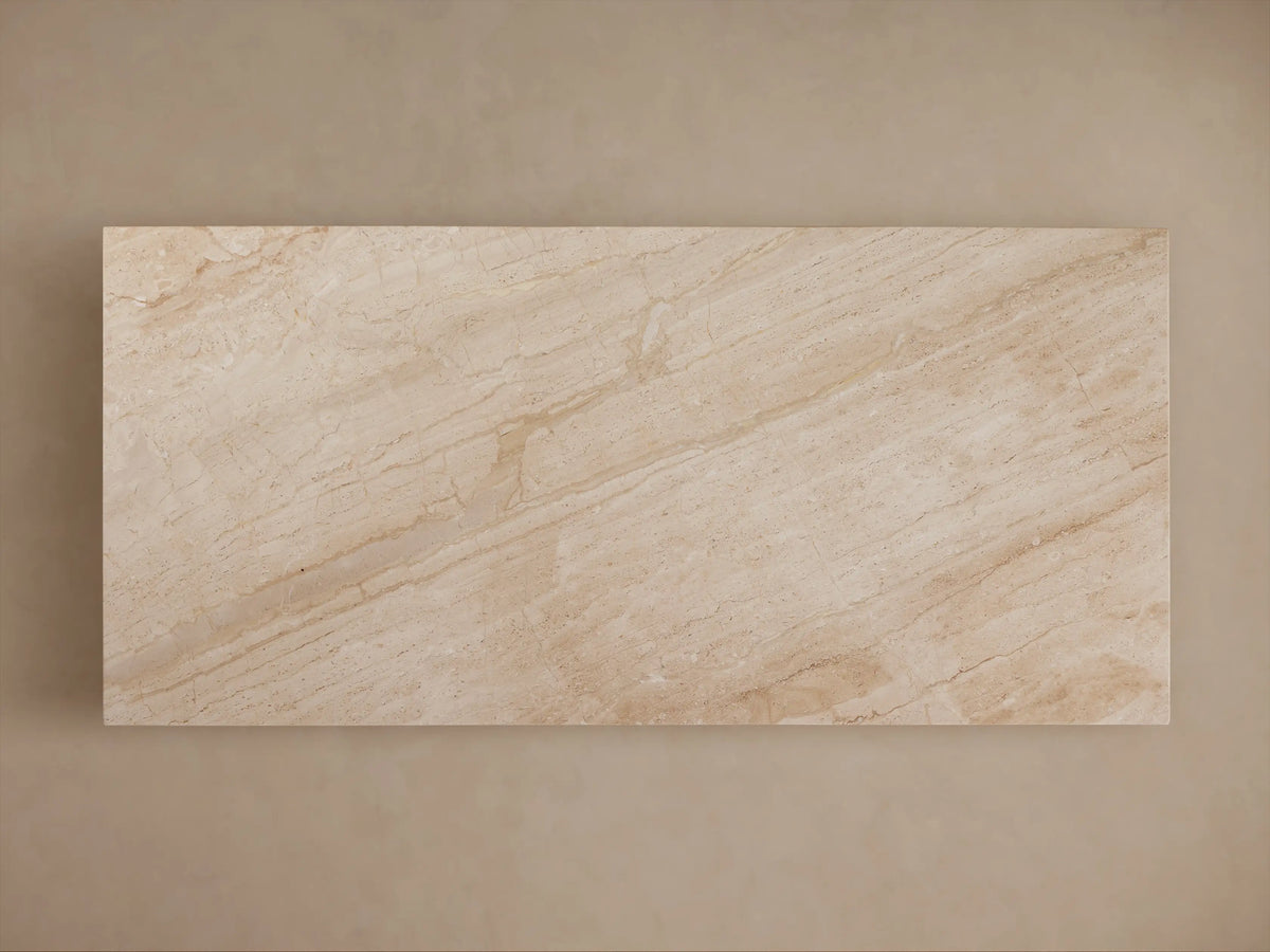 Beige marble table with a rectangular top and a geometric, trapezoidal base. The surface features subtle veining patterns.