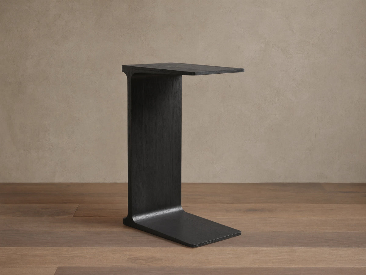 Front view of the ebony Iva C Table, featuring its sculptural single-leg frame of red oak veneer.