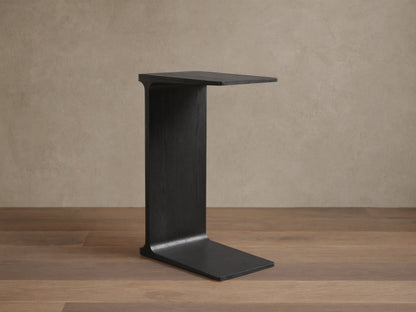 Front view of the ebony Iva C Table, featuring its sculptural single-leg frame of red oak veneer.