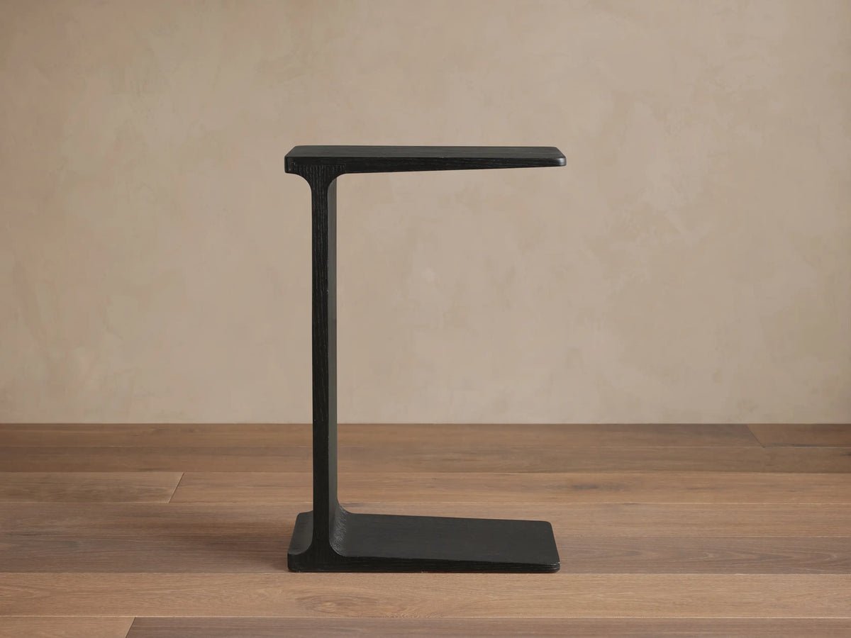 Front view of the ebony Iva C Table, featuring a sculptural single-leg frame and thin base.