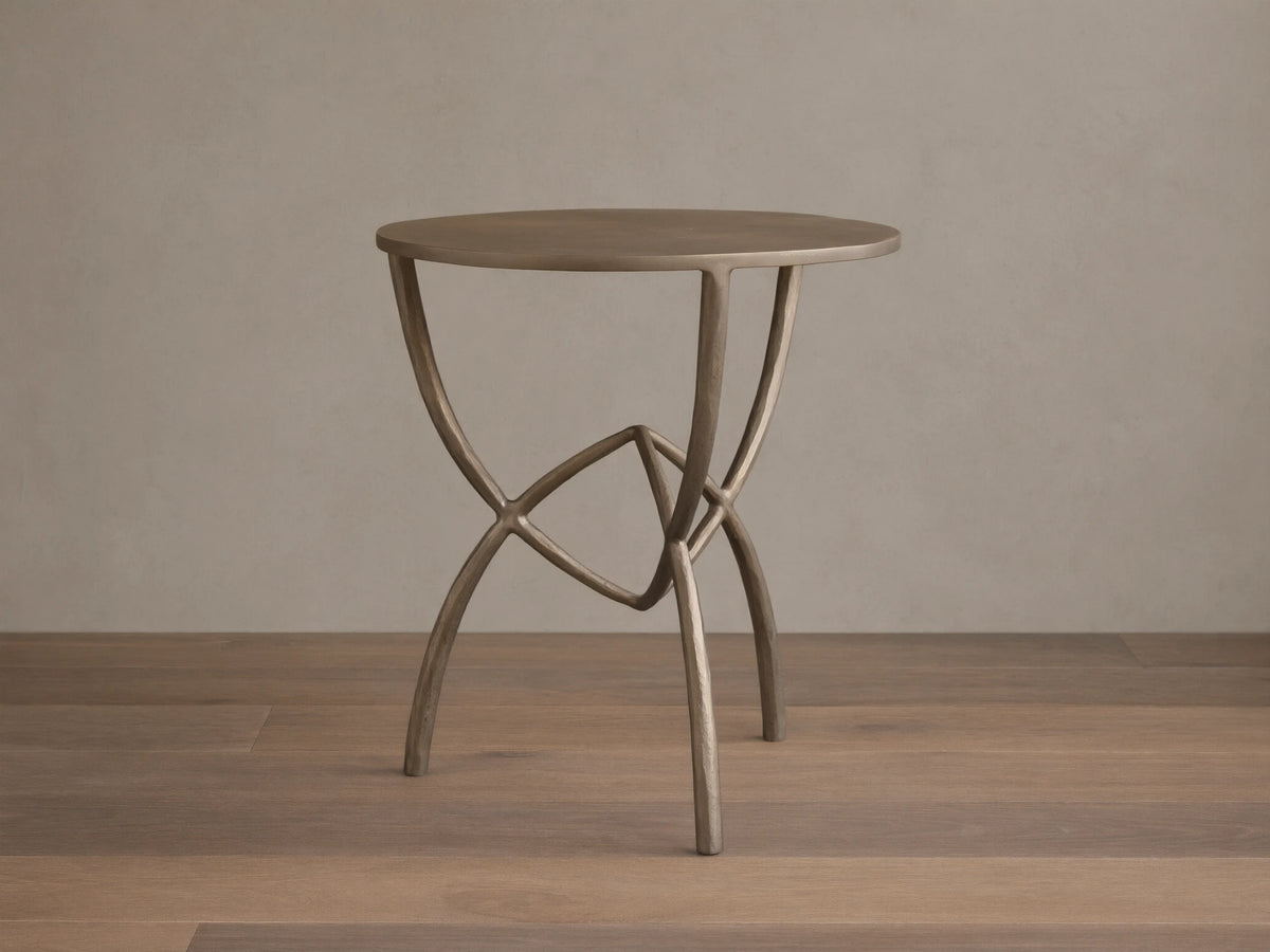 Front view of a bronze-toned Jedrek End Table with a circular top and sculptural, hand-pounded metal legs.