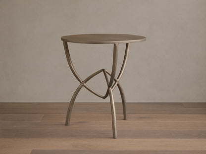 Front view of a bronze-toned Jedrek End Table with a circular top and sculptural, hand-pounded metal legs.