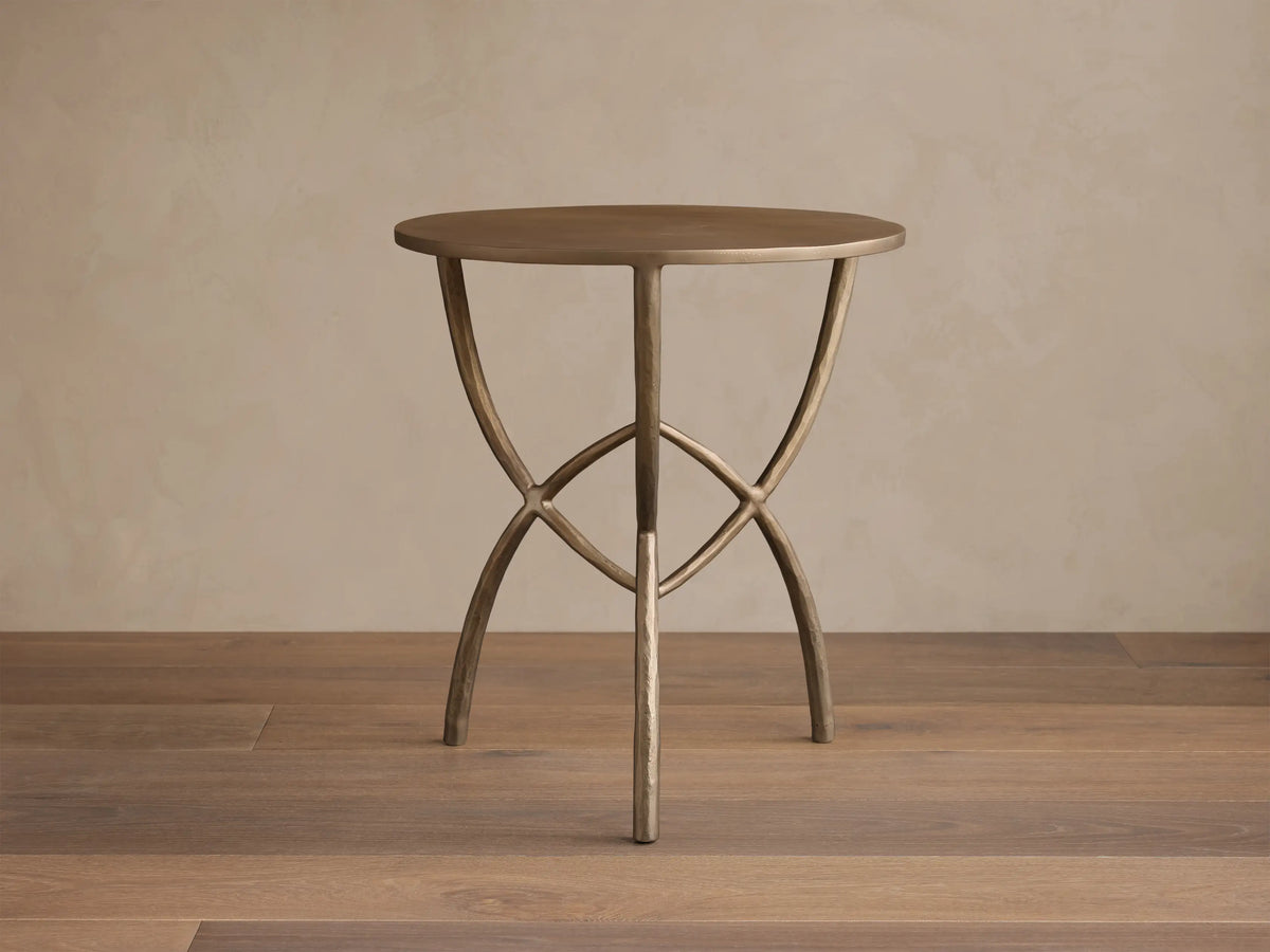 Front view of a bronze-toned Jedrek End Table with a circular top and sculptural, hand-pounded metal legs.