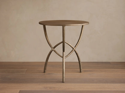Front view of a bronze-toned Jedrek End Table with a circular top and sculptural, hand-pounded metal legs.