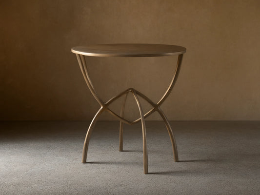 Front view of a bronze-toned Jedrek End Table with a circular top and sculptural, hand-pounded metal legs.