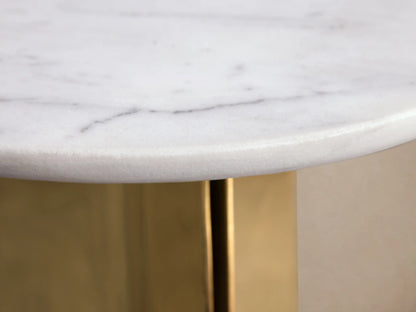 Jorah Martini Table with round white marble top and angular gold metal base, standing on wooden floor against beige wall.