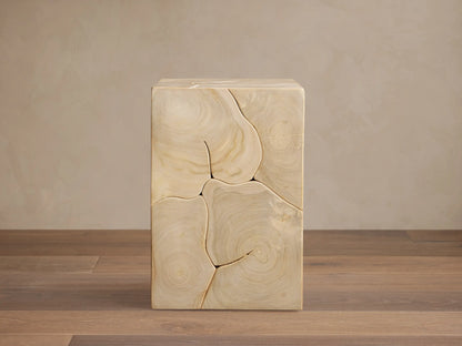 Kalmar Pedestal made of natural teak wood, showing organic shapes and distinct cracks. Light brown with visible grain patterns, placed on wooden floor.