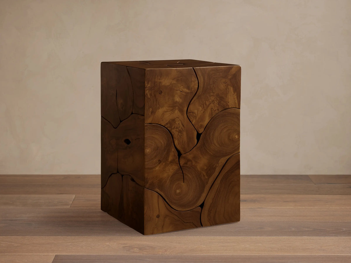 Kalmar Pedestal in natural teak wood featuring organic cracks, knots, and swirling patterns on a smooth, cube-shaped design.