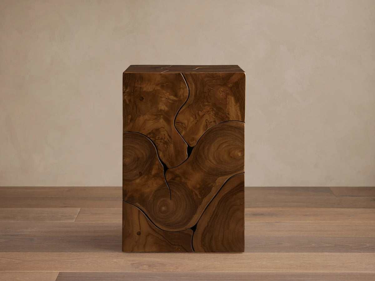 Kalmar Pedestal in natural teak wood featuring organic cracks, knots, and swirling patterns on a smooth, cube-shaped design.