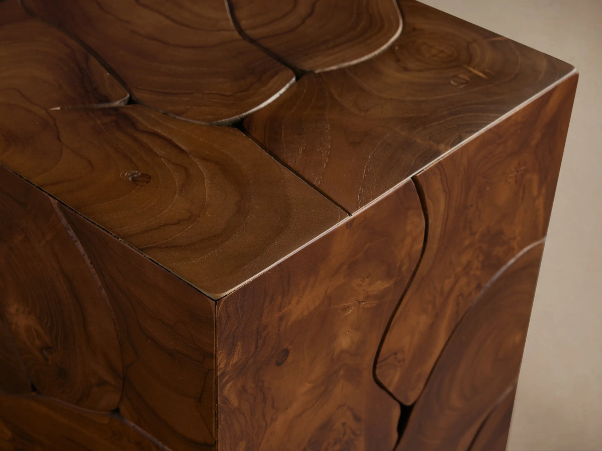 Kalmar Pedestal made of natural teak wood with organic shapes, visible cracks, and rich patina. Stands on wooden floor.